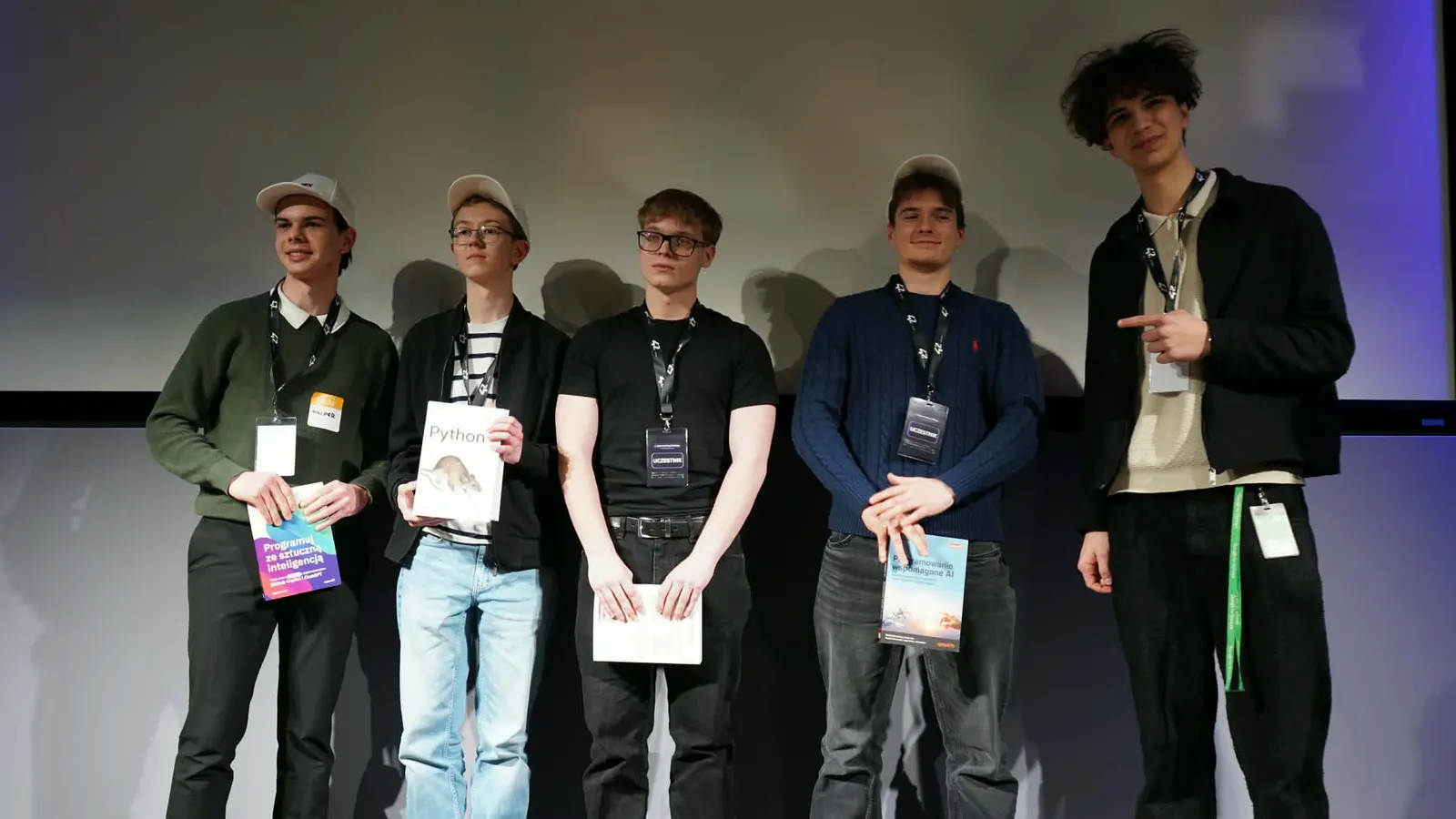 Five people on stage holding diplomas at the hackathon