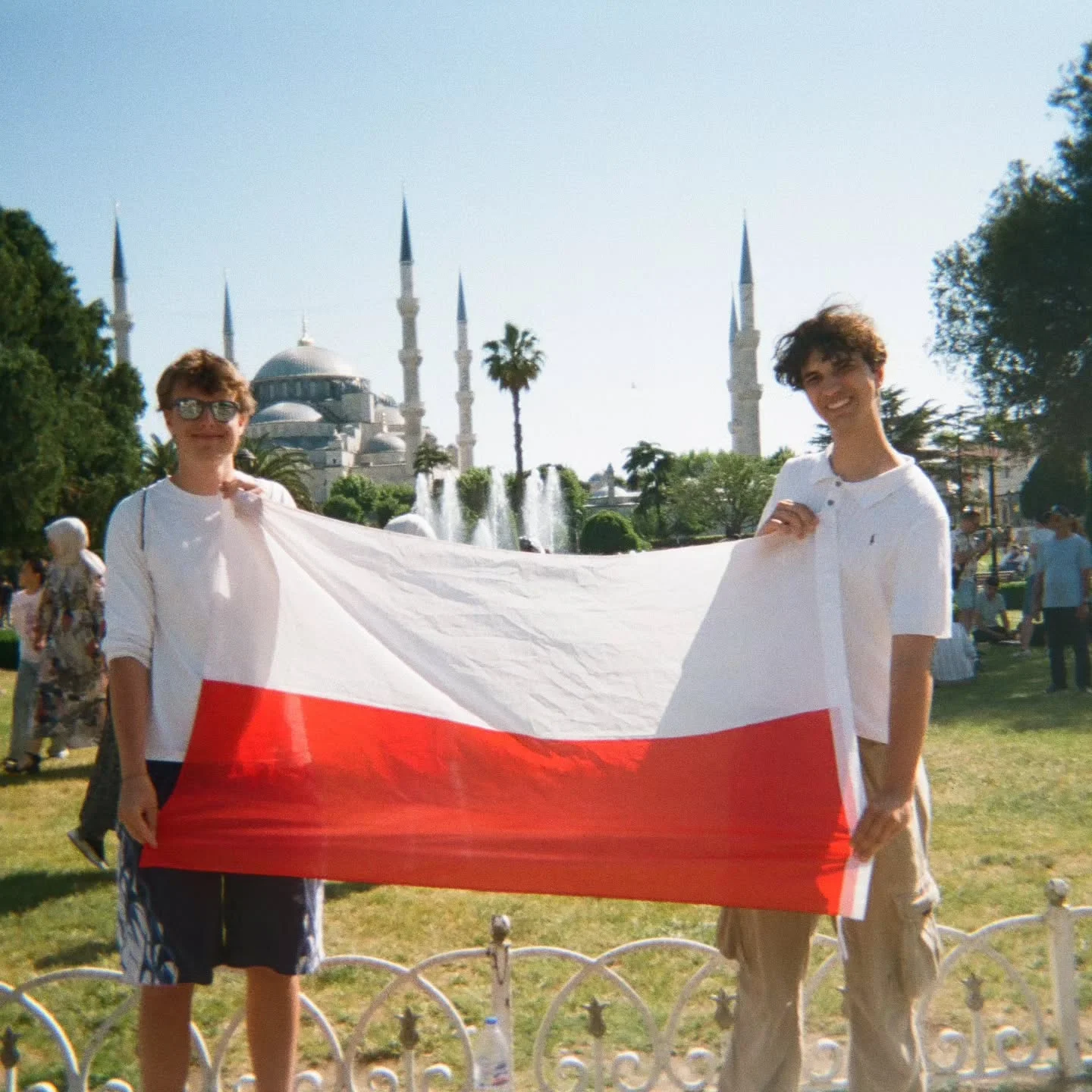Two friends holding a Polish flag in front of the Blue Mosque in Istanbul
