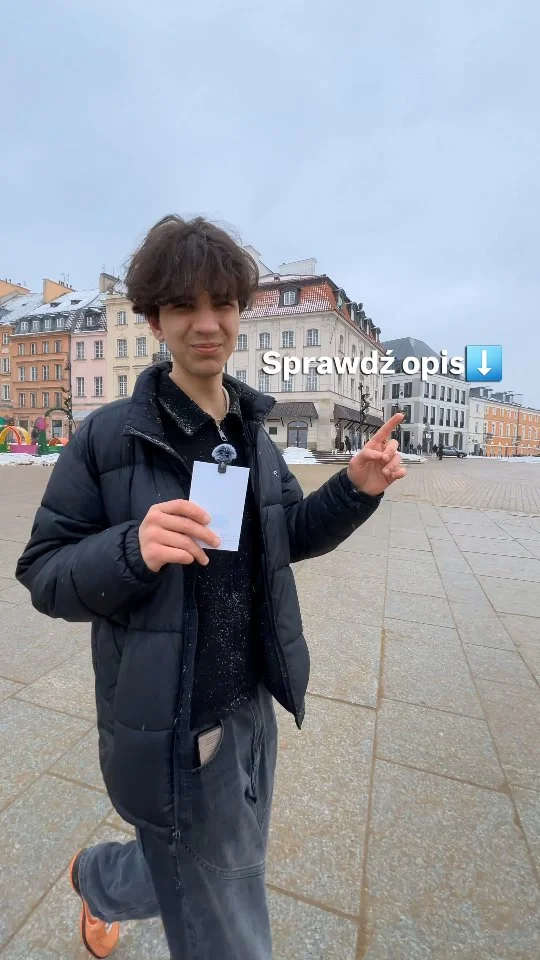 Dominik holding a phone in Warsaw's Old Town, cover of the reel about free tools for students
